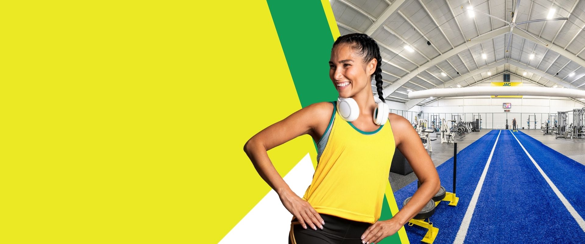 Member smiling at The Janesville Athletic Club indoor training area with blue turf track and modern strength equipment — promoting 30 Days Free gym offer in Janesville, WI.