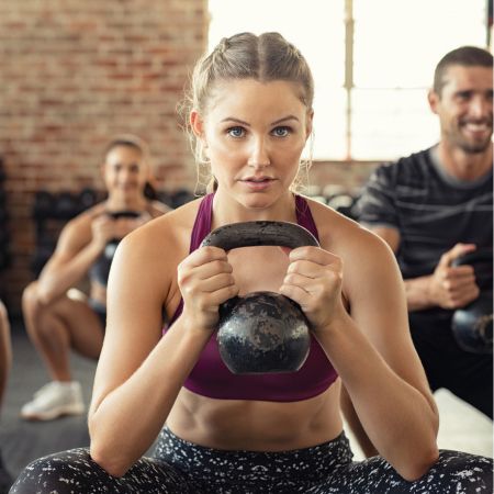 Stock photo of a group fitness strength workout with kettlebell for Janesville Athletic Club Strong class of the month post