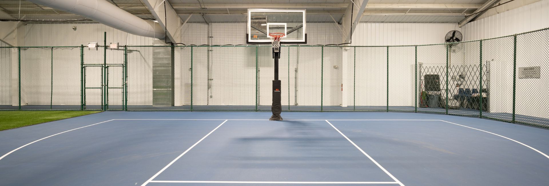 A view of the indoor basketball court at Janesville Athletic Club with a clear, open layout for gym schedule activities.