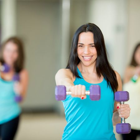 Woman lifting free weights during a Power Pump group fitness class at our Janesville gym.